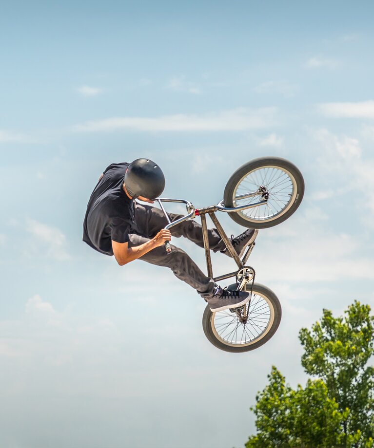 Niedrigwinkelansich eines Mannes der einen Stunt auf einem BMX Bike gegen den Himmel ausführt | © EyeEm | Freepik