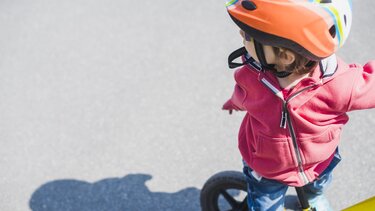 Ein Kind sitzt auf einem Kinderfahrrad draussen | © Freepik